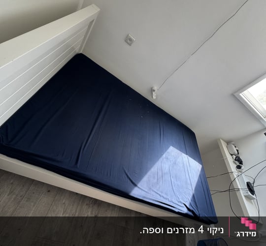 מיטת יחיד בעלת שלד לבן ומזרן מכוסה בסדין כחול